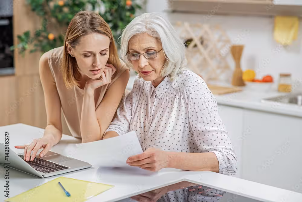 Meeting with mother and daughter going over paperwork and working on a laptop together 