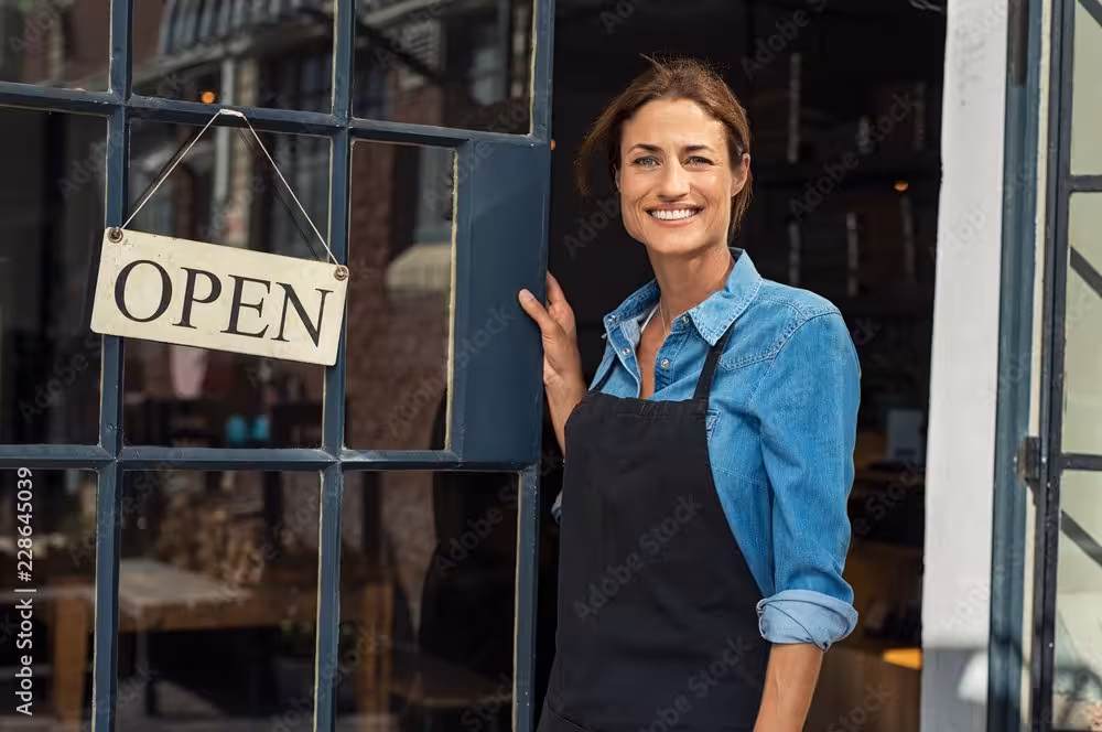 Women standing beside an open sign with an apron on